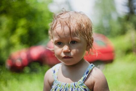 Toddler girl playing with water from a sprinklerの写真素材