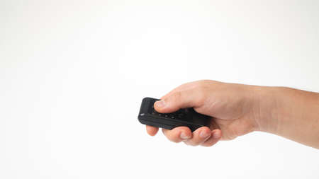 A mans hand holds a small remote control on a white backgroundの写真素材