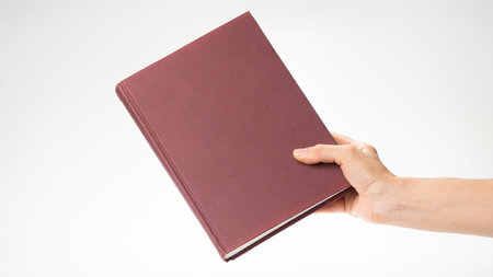 A womans hand holds a closed book, there is room for an inscription on the cover