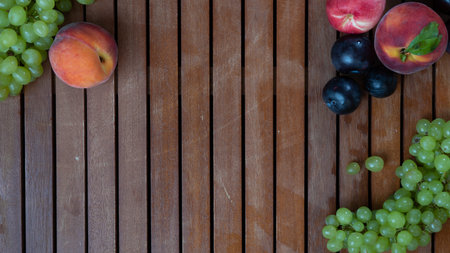 Fruits on a wooden background with space for inscription - grapes, peach, plum
