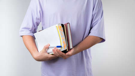 Male student holds textbooks and notebooks for classes in an educational institution with his armpitの写真素材