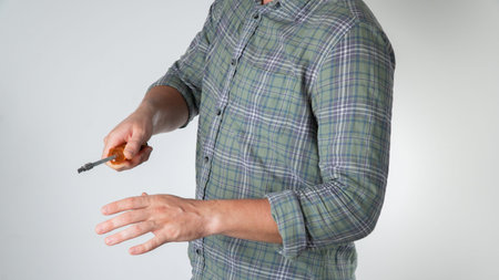 A man with a screwdriver in his hand gesture screws a close-up screw on a white background