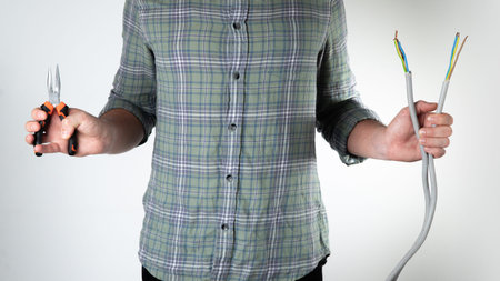 Male electrician holds wire cutters and wires on a white background