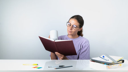 A girl reads a book or textbook and drinks coffee - study, homework