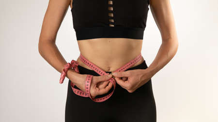 Weight loss, a woman with a measuring tape makes a measurement of the waist volumeの写真素材