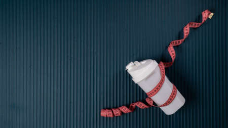 Shaker wrapped with measuring tape on yoga mat with space for inscription, sports backgroundの写真素材