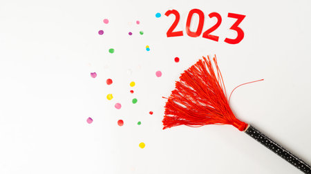 clapperboard with red tassel and confetti and the number 2023 on a white background, new year. high...