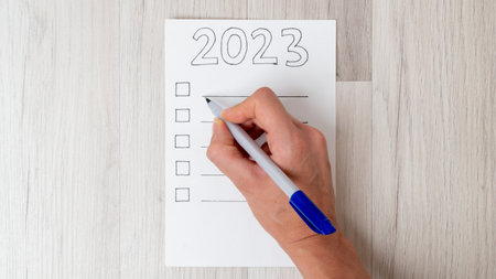 A woman's hand fills the checklist with a pen for the new year 2023. High quality photoの写真素材