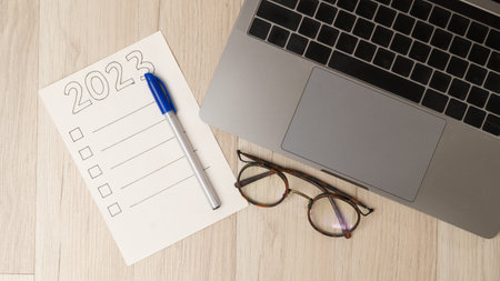 To-do list for 2023, glasses and an open laptop on a wooden table, a checklist for the new year....