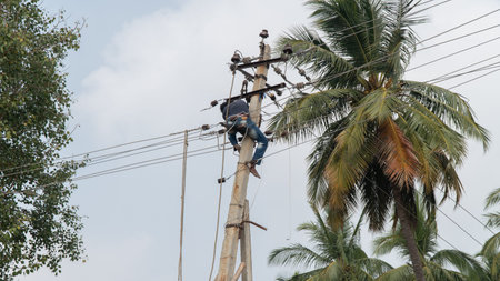 An electrician on a pole fixing electrical wires