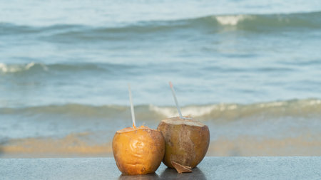 Two coconuts with straws for drinking on the background of the seaの写真素材