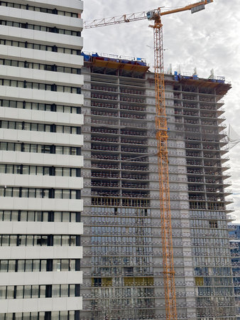 A construction crane erects a skyscraper against the background of a finished building
