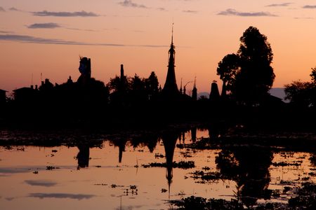 buddha statue and temple during sunset on a lakeの写真素材