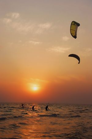 silhouettes of kite surfers at sunsetの写真素材
