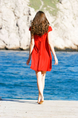 young girl in red dress on the seaの写真素材