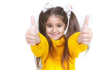 young girl showing her thumbs up over whiteの写真素材