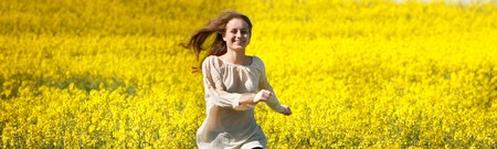 young happy girl running in yellow flower fieldの写真素材