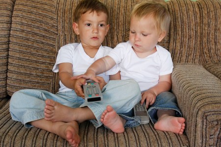 two kids watching tv at homeの写真素材