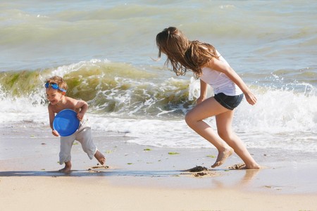 mother and son playing frisbee on beachの写真素材
