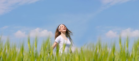 happy girl in green grass over sky backgroundの写真素材