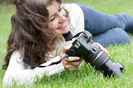 young smiling girl taking picture outdoorsの写真素材