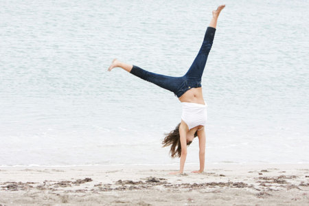 young girl doing gymnastics on beach