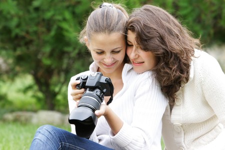 two girl looking through pictures on digital cameraの写真素材