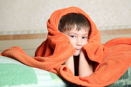 cute young boy hiding under blanketの写真素材