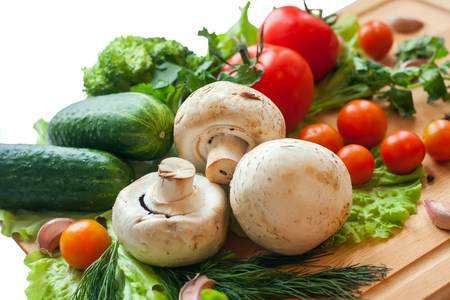 Vegetables on wood background, mushrooms, cucumbers, tomatoes, broccoli, lettuce, dill, parsley and pepper on isolated white backgroundの写真素材