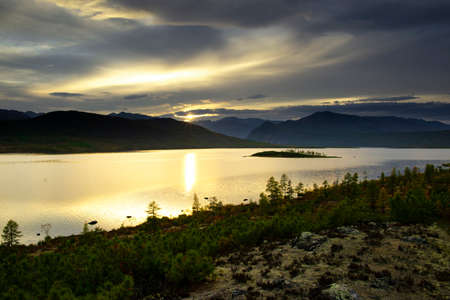 Russia. Magadan Region. A beautiful forest lake against the backdrop of the Big Anngachak mountain range. Autumn in the vicinity of Lake Jack London.の写真素材