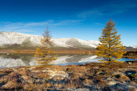 Russia. Magadan Region. A beautiful forest lake against the backdrop of the Big Anngachak mountain range. Autumn in the vicinity of Lake Jack London.の写真素材