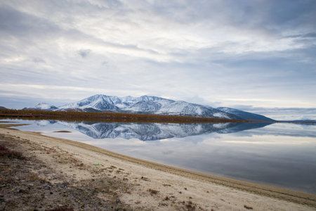 Russia. Magadan Region. Beautiful Lake Momontay against the backdrop of a snowy mountain range. Late autumn in the vicinity of Lake Momontay.の写真素材