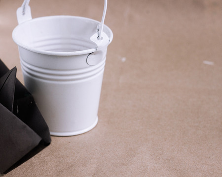 vintage small white bucket and black origami boat on brown backgroundの写真素材