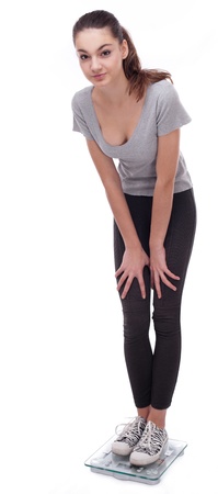 Teenager standing on scales. Isolated on a white background.の写真素材