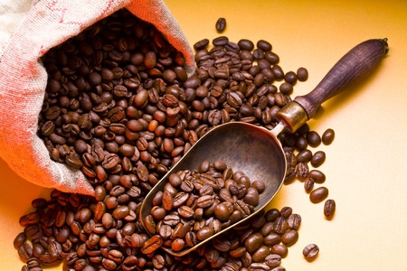 Sack of coffee beans and scoop. On a dark yellow background.の写真素材