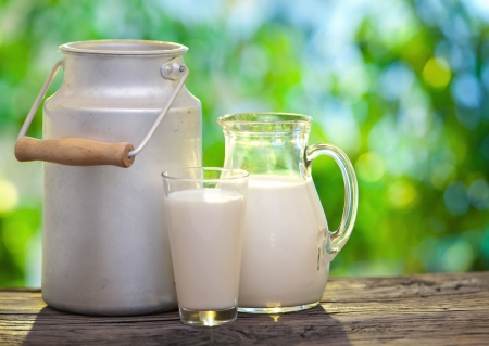 Milk in various dishes on the old wooden table in an outdoor setting.の写真素材