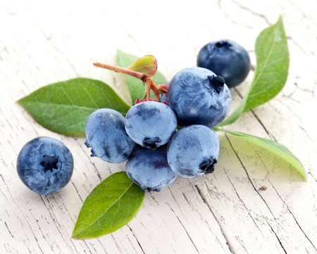 Blueberries with leaves on a wooden table. Studio isolated.の写真素材