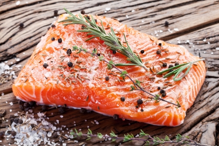 Salmon filet with spices on a wooden carving board. Macro shot.の写真素材