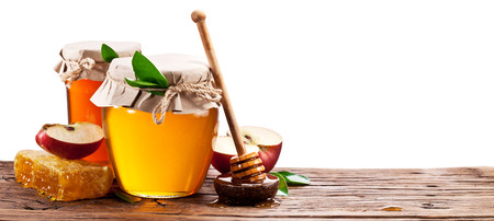 Glass can full of honey, apples and honeycombs on old wooden table. Clipping paths.の写真素材