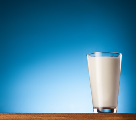 Glass of milk on a blue background.の写真素材