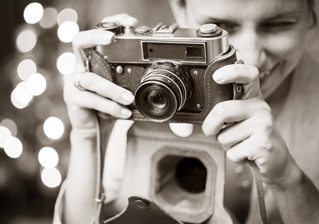 Smiling woman photographed retro camera. Black - white image processing.