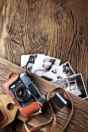 Old rangefinder camera and black-and-white photos on the old wooden table.の写真素材