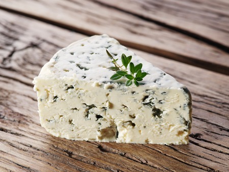 Slices of Danish Blue cheese on an old wooden table.の写真素材
