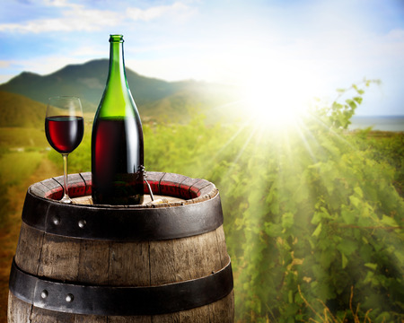 Still-life with glass of wine and bottle on the barrel in the vineyard.の写真素材