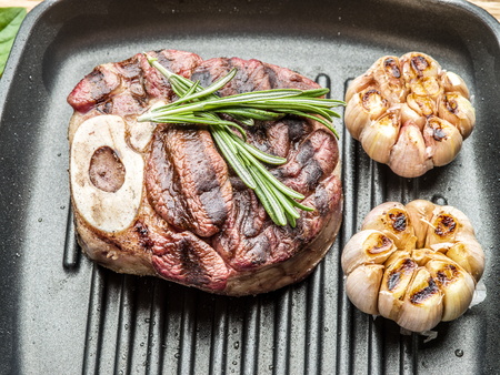 Beef steak with spices on pan on wooden table.の写真素材