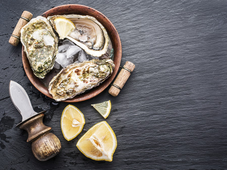 Raw oysters on the graphite board.の写真素材