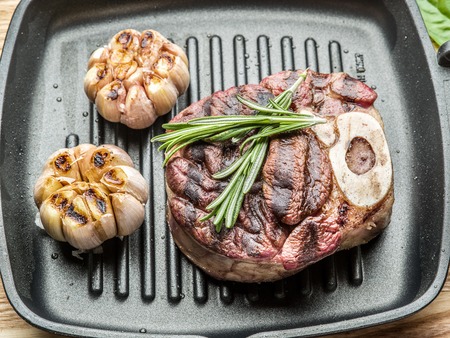 Beef steak with spices on pan on wooden table.の写真素材