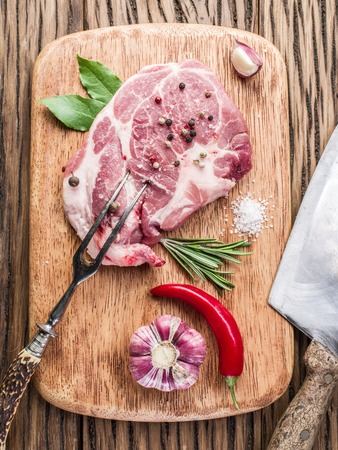 Raw pork steak with spices on the wooden cutting board.の写真素材