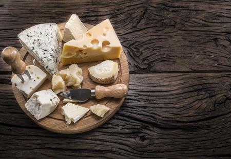 Variety of cheeses on a wooden board.の写真素材