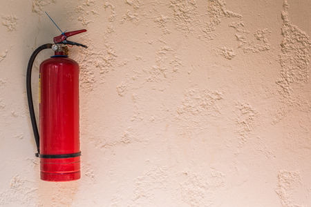 Red fire extinguisher fixed on the wall of the house.の写真素材
